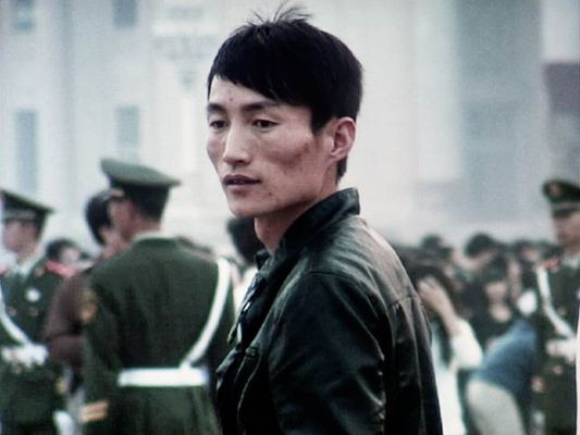 Fotografie eines jungen Mannes in Lederjacke vor Uniformierten